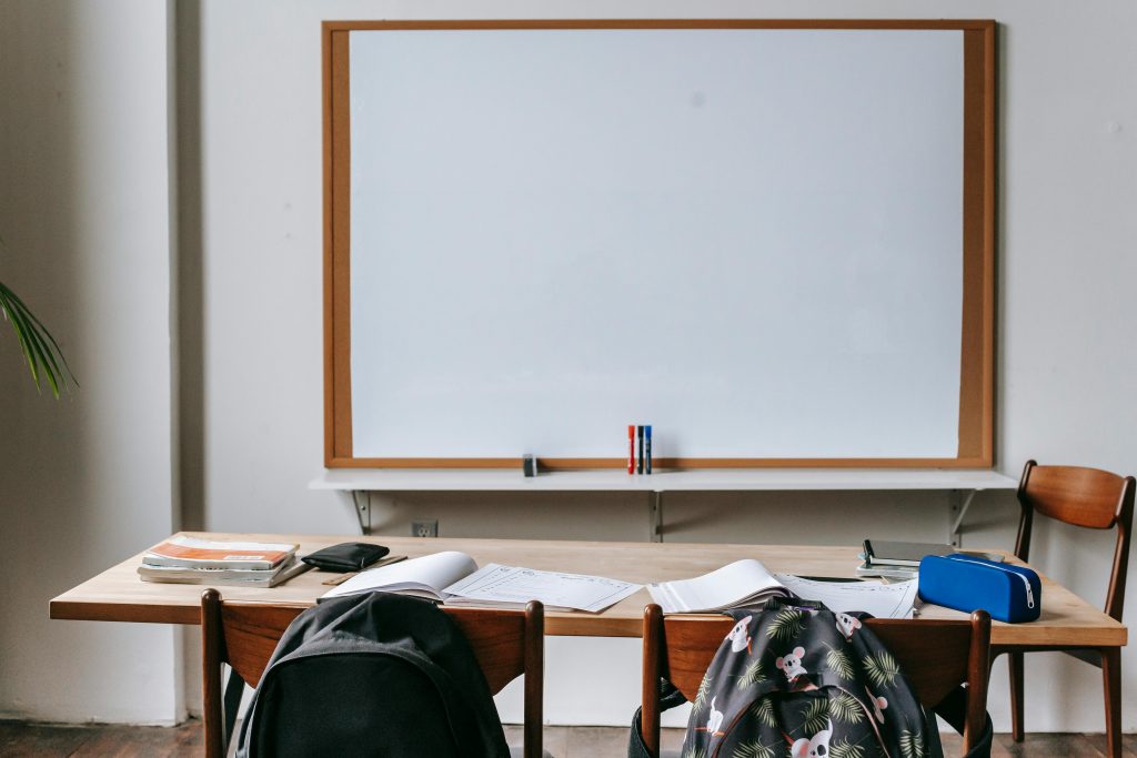 Empty classroom with wooden desks, chairs, and a large whiteboard. Ideal for educational themes.
